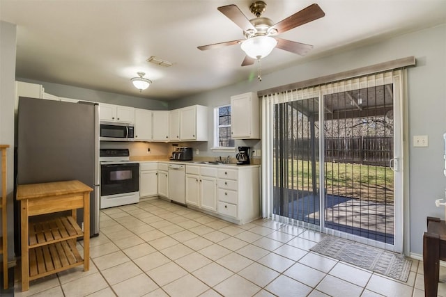 kitchen with stainless steel microwave, visible vents, white dishwasher, electric range, and white cabinetry