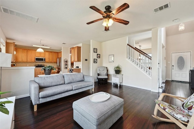 living room with stairway, visible vents, wood-type flooring, and ceiling fan