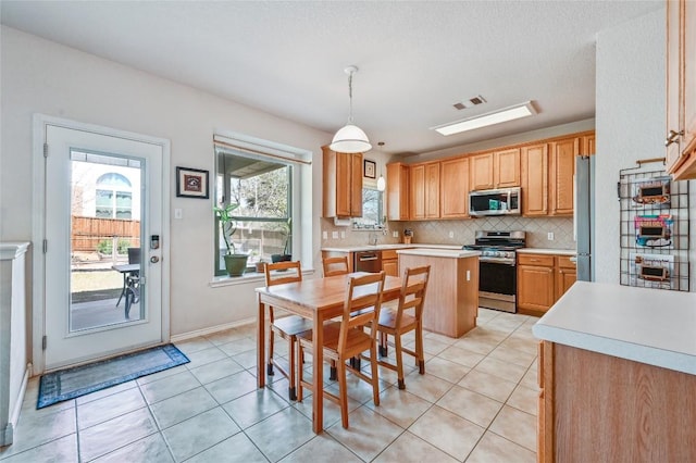 kitchen with visible vents, backsplash, stainless steel appliances, light tile patterned flooring, and light countertops