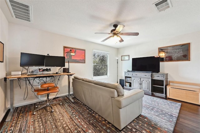 living area featuring a ceiling fan, wood finished floors, visible vents, and a textured ceiling