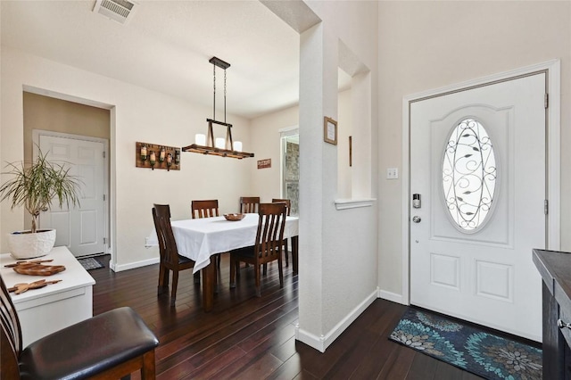 entryway featuring visible vents, dark wood-type flooring, a notable chandelier, baseboards, and a healthy amount of sunlight