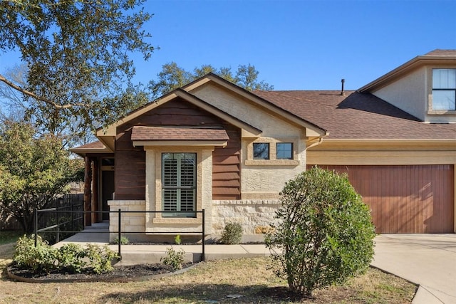 view of front of home featuring stone siding, concrete driveway, a shingled roof, and a garage