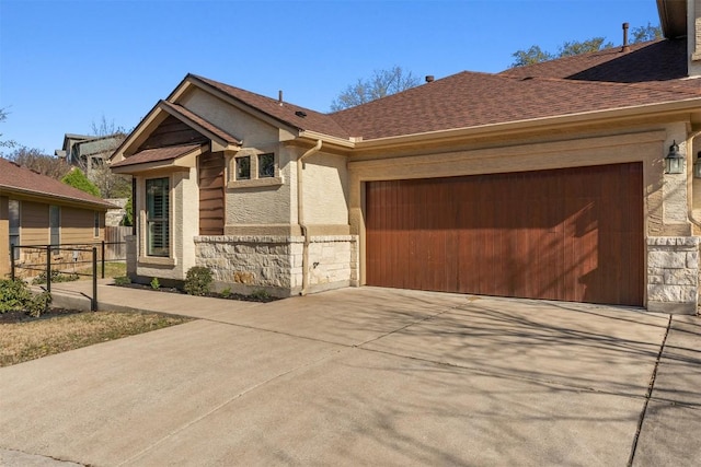 view of front of property with a shingled roof, fence, concrete driveway, stone siding, and an attached garage