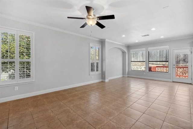 tiled empty room with visible vents, arched walkways, crown molding, baseboards, and ceiling fan