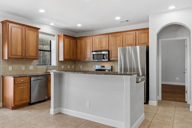 kitchen with brown cabinetry, visible vents, stainless steel appliances, and light tile patterned floors