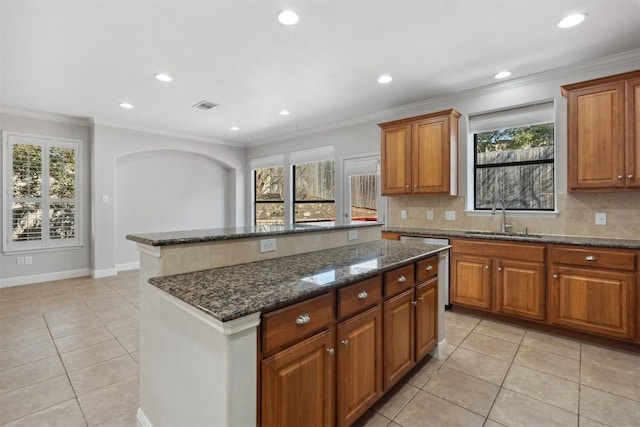 kitchen featuring decorative backsplash, a kitchen island, visible vents, and a sink