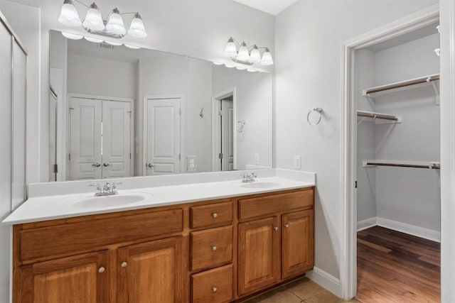 full bathroom with a sink, baseboards, double vanity, and tile patterned floors