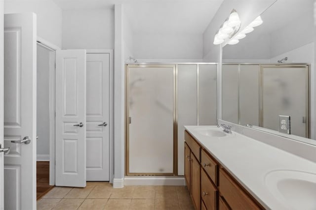 full bath with tile patterned floors, a shower stall, double vanity, and a sink