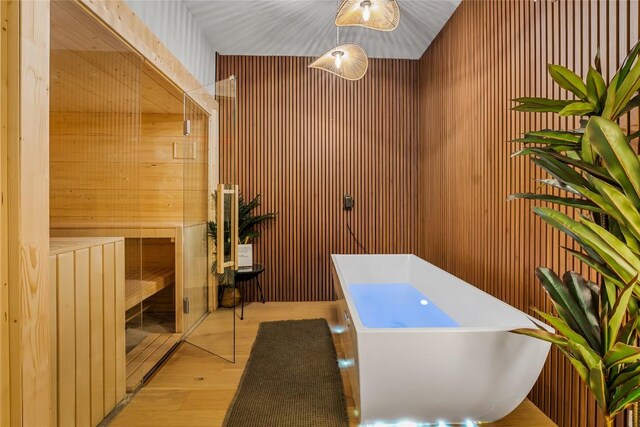 2505 Thornton Rd Unit 1105, Austin, TX 78704 - bathroom featuring wooden walls, wood finished floors, a soaking tub, and a sauna / steam room