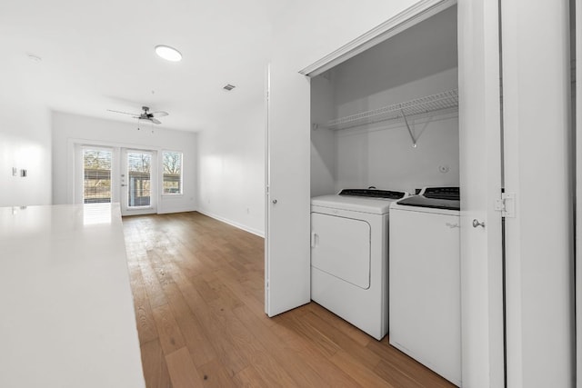 laundry room with baseboards, ceiling fan, washer and clothes dryer, light wood-type flooring, and laundry area