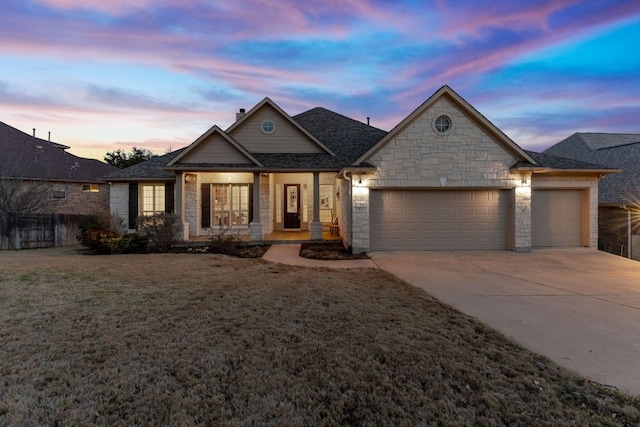 view of front of home featuring fence, an attached garage, concrete driveway, stone siding, and a lawn