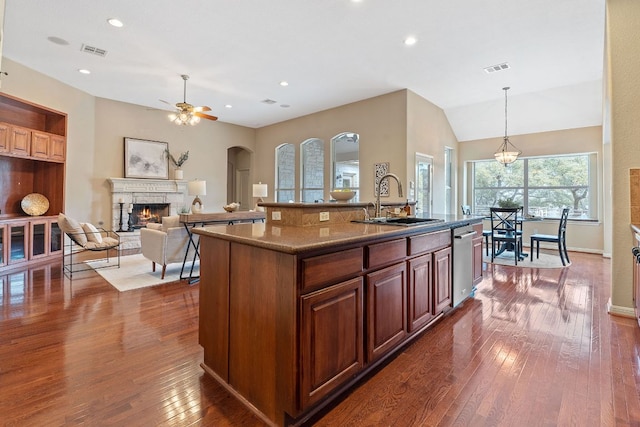 kitchen featuring visible vents, a ceiling fan, a sink, stainless steel dishwasher, and a stone fireplace