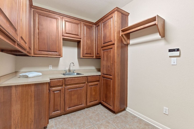 kitchen with brown cabinetry, light tile patterned floors, light countertops, and a sink