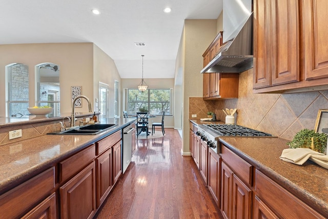 kitchen featuring visible vents, a sink, stainless steel appliances, wall chimney exhaust hood, and tasteful backsplash