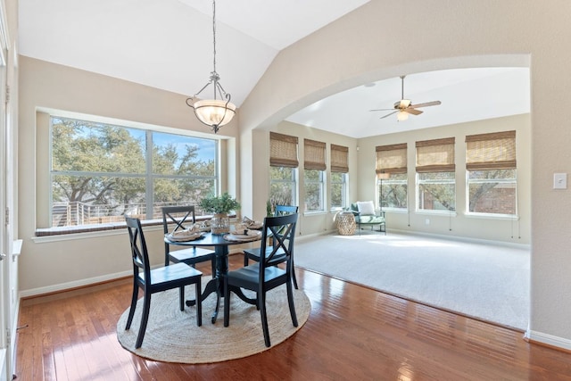 dining room featuring hardwood / wood-style floors, vaulted ceiling, a ceiling fan, and arched walkways