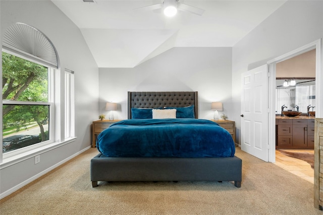 bedroom with baseboards, vaulted ceiling, ensuite bath, a ceiling fan, and a sink