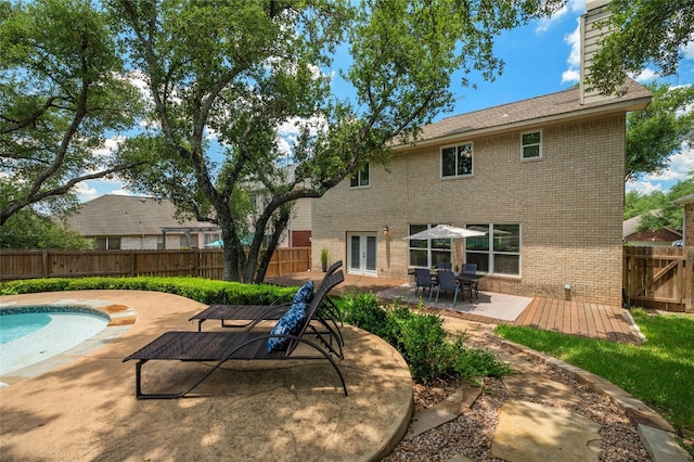 rear view of house with a patio, a fenced in pool, a fenced backyard, french doors, and brick siding