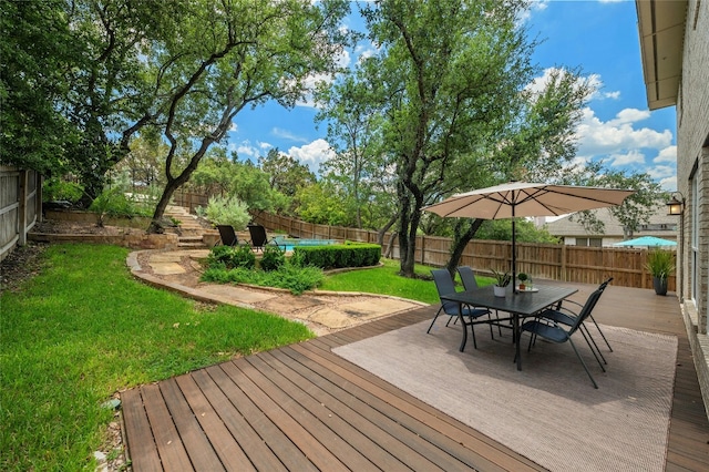 deck featuring outdoor dining space, a lawn, and a fenced backyard