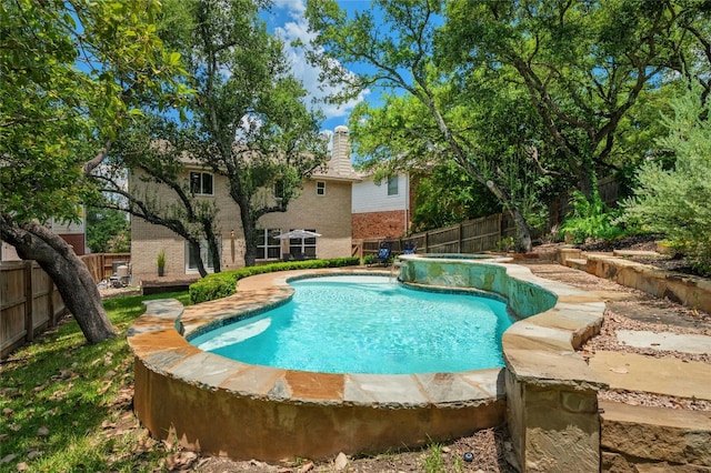 view of swimming pool with a fenced backyard and a pool with connected hot tub