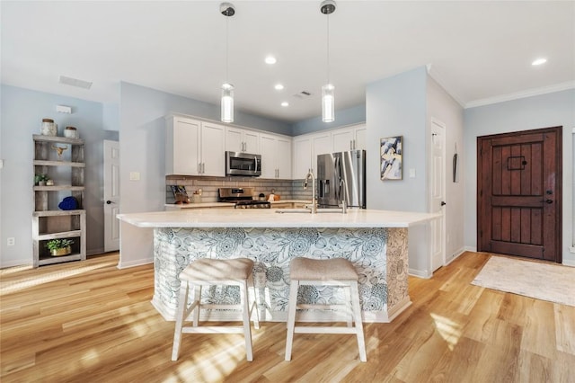 kitchen with a kitchen breakfast bar, tasteful backsplash, white cabinetry, stainless steel appliances, and light countertops