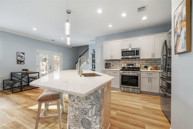 kitchen with tasteful backsplash, visible vents, french doors, stainless steel appliances, and a sink