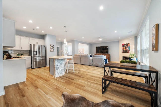 kitchen featuring stainless steel fridge, a breakfast bar, white cabinets, and light countertops