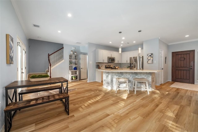 kitchen with tasteful backsplash, light wood-type flooring, light countertops, stainless steel appliances, and white cabinetry