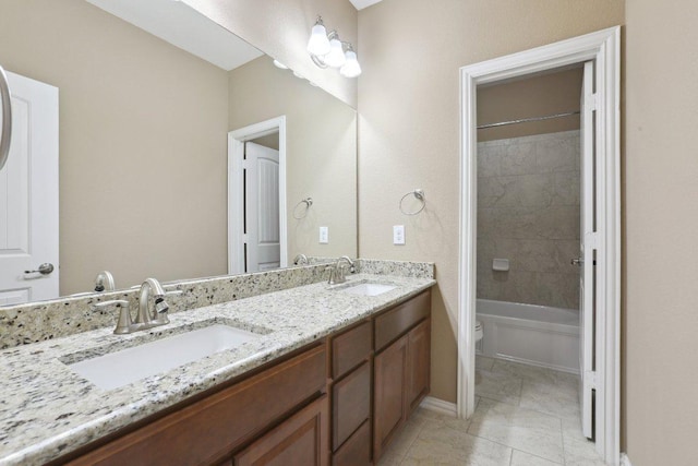 full bath with double vanity, toilet, shower / bath combination, and a sink