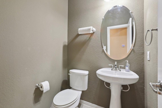 half bathroom with toilet and a textured wall