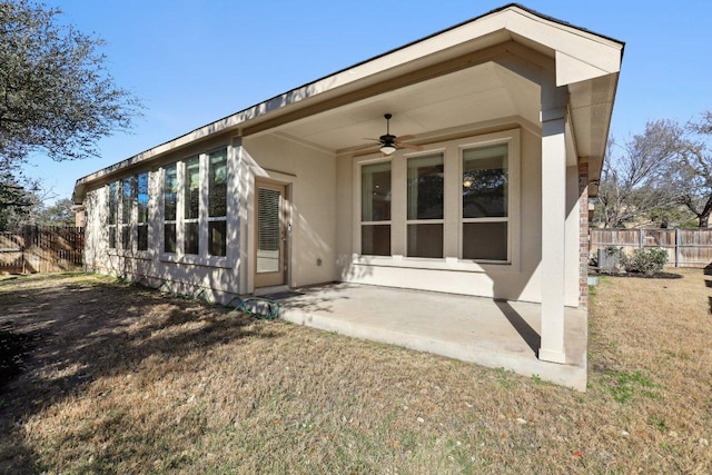 rear view of property featuring fence, a yard, ceiling fan, stucco siding, and a patio area