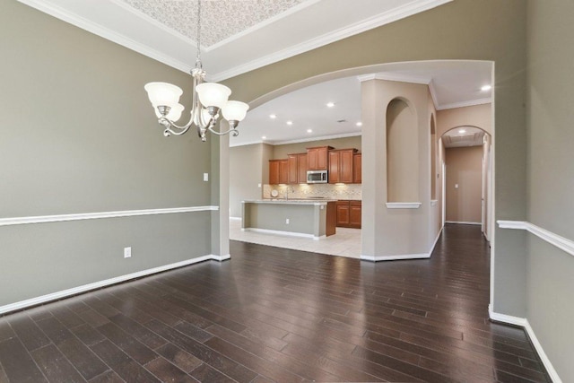 interior space with baseboards, arched walkways, light wood finished floors, and ornamental molding