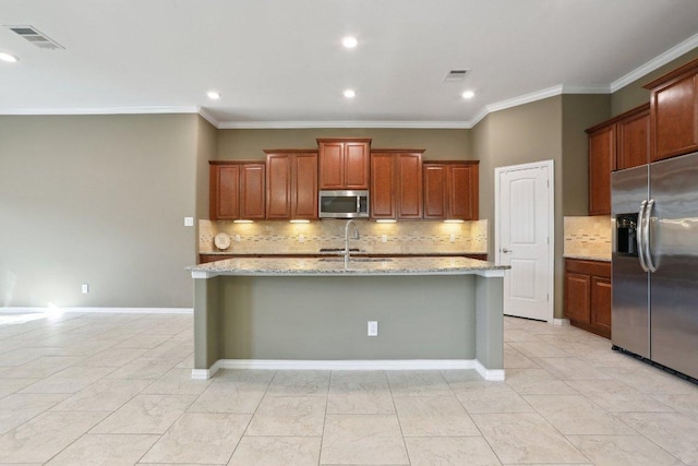 kitchen with a sink, stainless steel appliances, light stone countertops, and a center island with sink