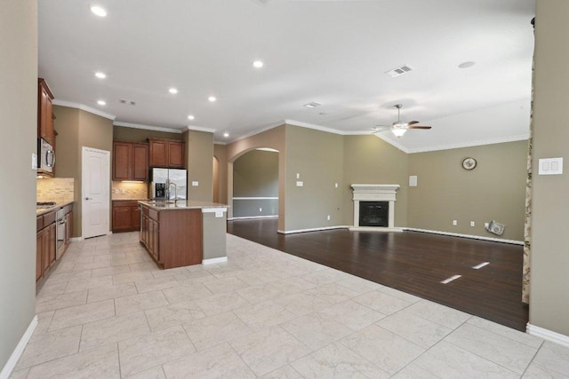 kitchen featuring visible vents, arched walkways, ceiling fan, stainless steel appliances, and open floor plan