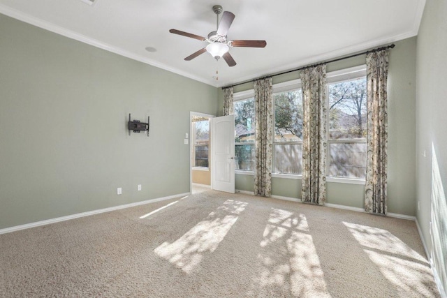 spare room with baseboards, carpet, ornamental molding, and a ceiling fan