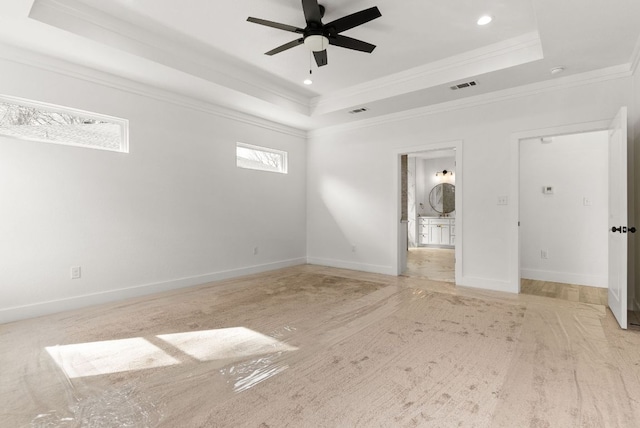 unfurnished bedroom with a tray ceiling, baseboards, visible vents, and ornamental molding