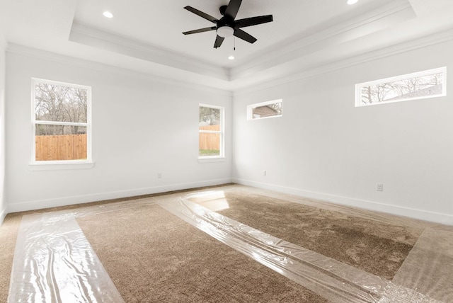 empty room featuring a tray ceiling, a ceiling fan, and baseboards