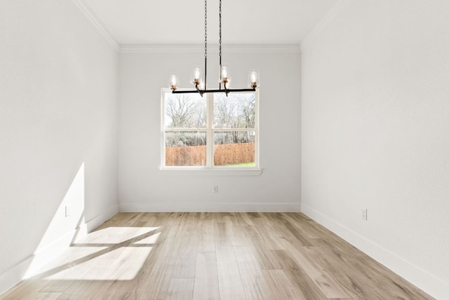 unfurnished dining area with baseboards, crown molding, an inviting chandelier, and wood finished floors