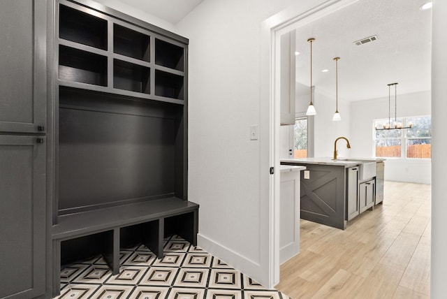 mudroom with visible vents, a notable chandelier, light wood-style flooring, a sink, and baseboards