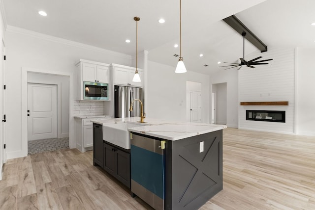 kitchen featuring lofted ceiling with beams, light wood finished floors, appliances with stainless steel finishes, and a sink