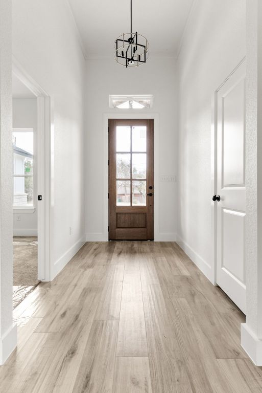 entryway with a wealth of natural light, baseboards, a notable chandelier, and light wood-style flooring