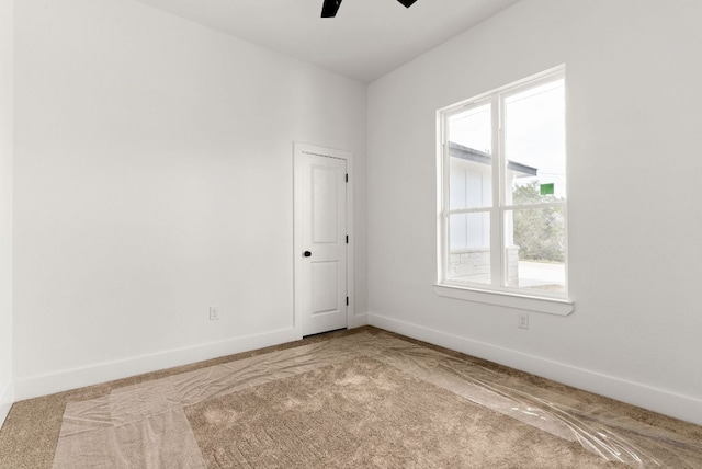 empty room featuring carpet flooring, baseboards, and ceiling fan