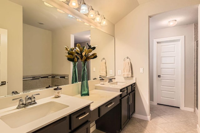 bathroom with a sink, baseboards, double vanity, and tile patterned floors