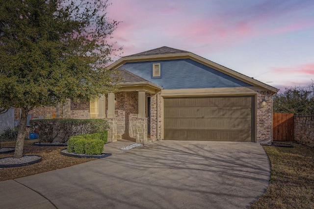 view of front of house with brick siding, driveway, a garage, and fence