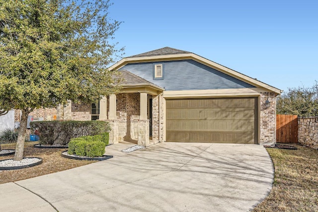 view of front of property featuring brick siding, driveway, an attached garage, and fence