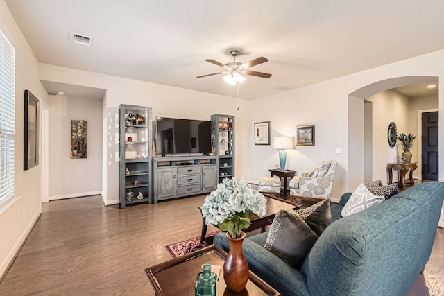 living room featuring visible vents, baseboards, ceiling fan, wood finished floors, and arched walkways