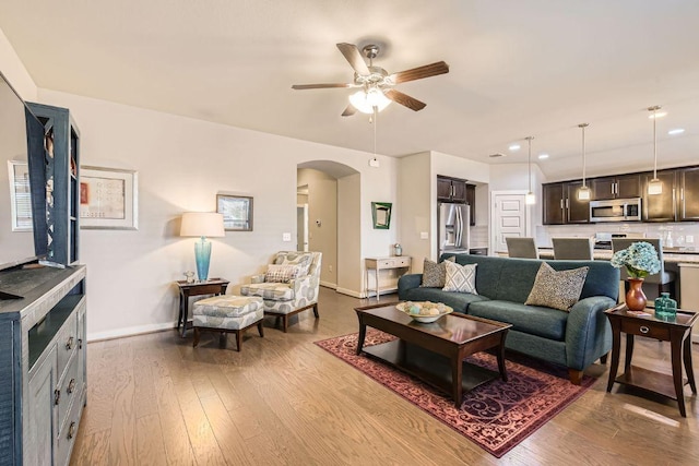 living room featuring baseboards, recessed lighting, arched walkways, a ceiling fan, and dark wood-style flooring