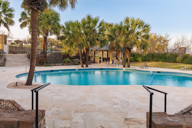 outdoor pool featuring a patio area, a gazebo, and fence