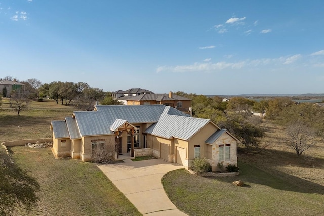 view of front of property featuring driveway, a standing seam roof, an attached garage, a front lawn, and metal roof