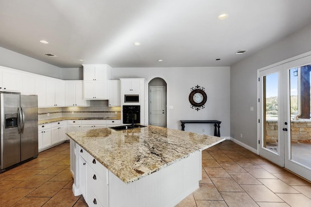 kitchen featuring visible vents, stainless steel fridge with ice dispenser, built in microwave, arched walkways, and backsplash