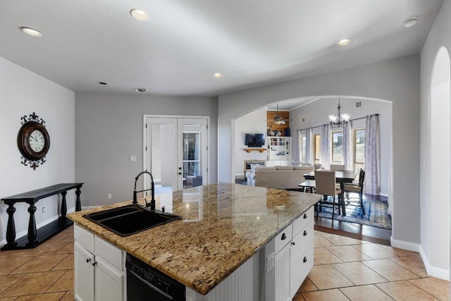 kitchen featuring dishwasher, arched walkways, a notable chandelier, white cabinetry, and a sink